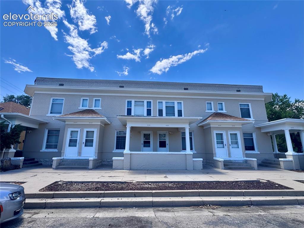 Caption: Multi-unit residential structure featuring a light-toned exterior finish and multiple entryways with