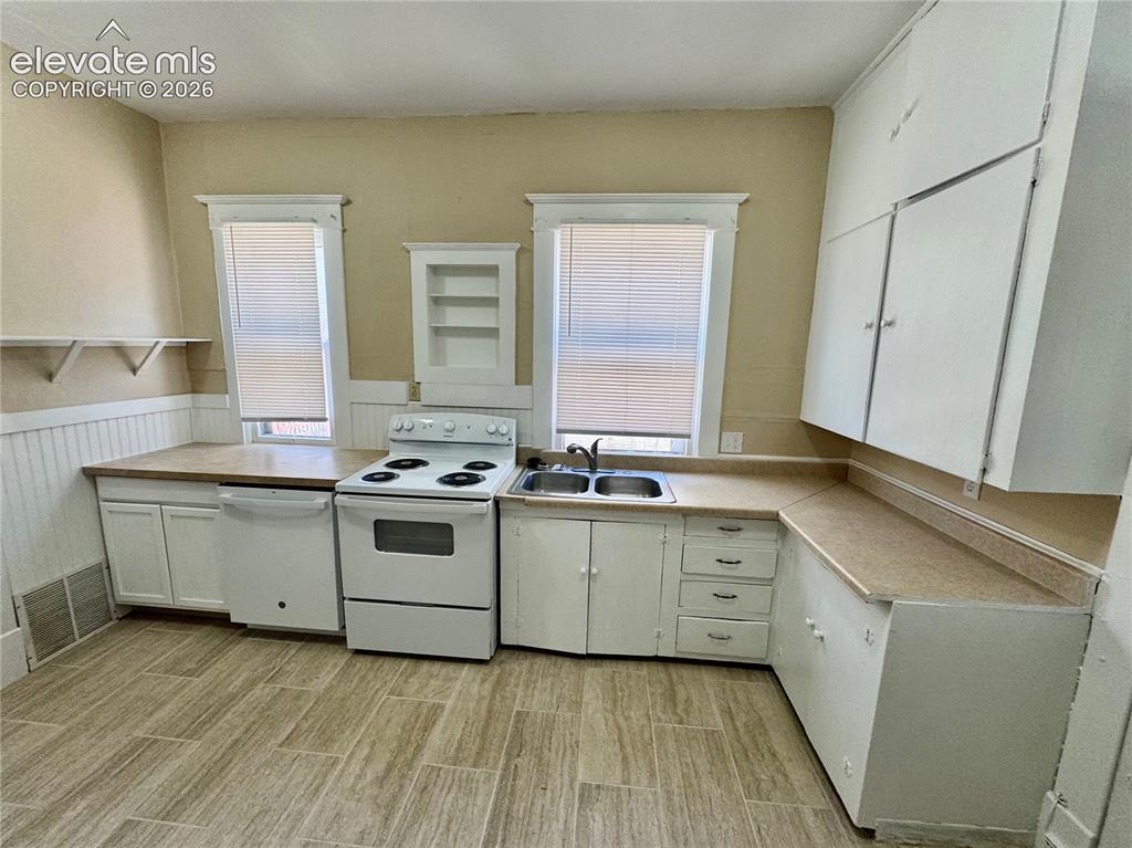 Image 16 of 50: Kitchen featuring white cabinetry, a double basin sink, and a built-in refr