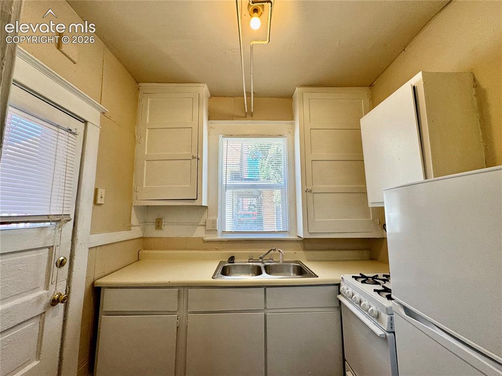 Image 17 of 48: Kitchen featuring a double basin sink, window, white cabinetry, and white a