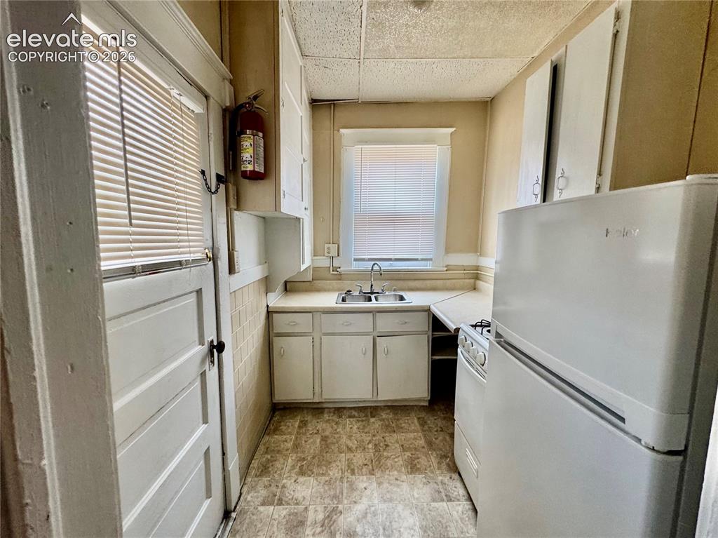 Image 18 of 50: Kitchen featuring a double basin sink, window, white cabinetry, and white a