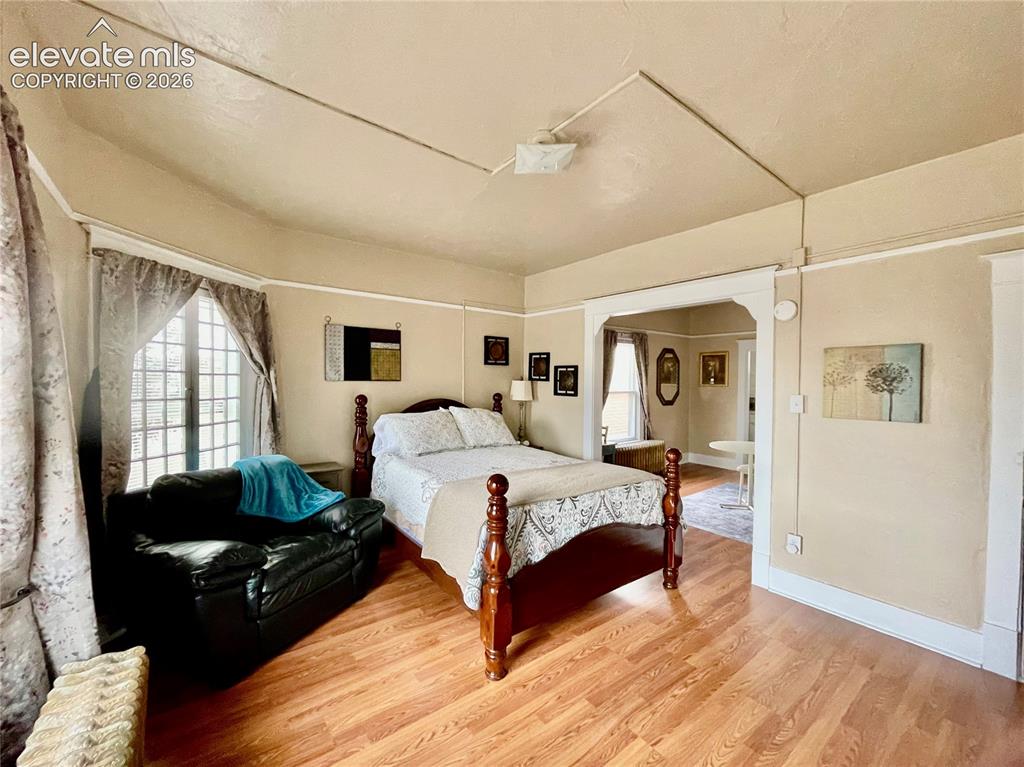 Image 31 of 48: Spacious primary bedroom with wood-finish flooring, decorative ceiling deta