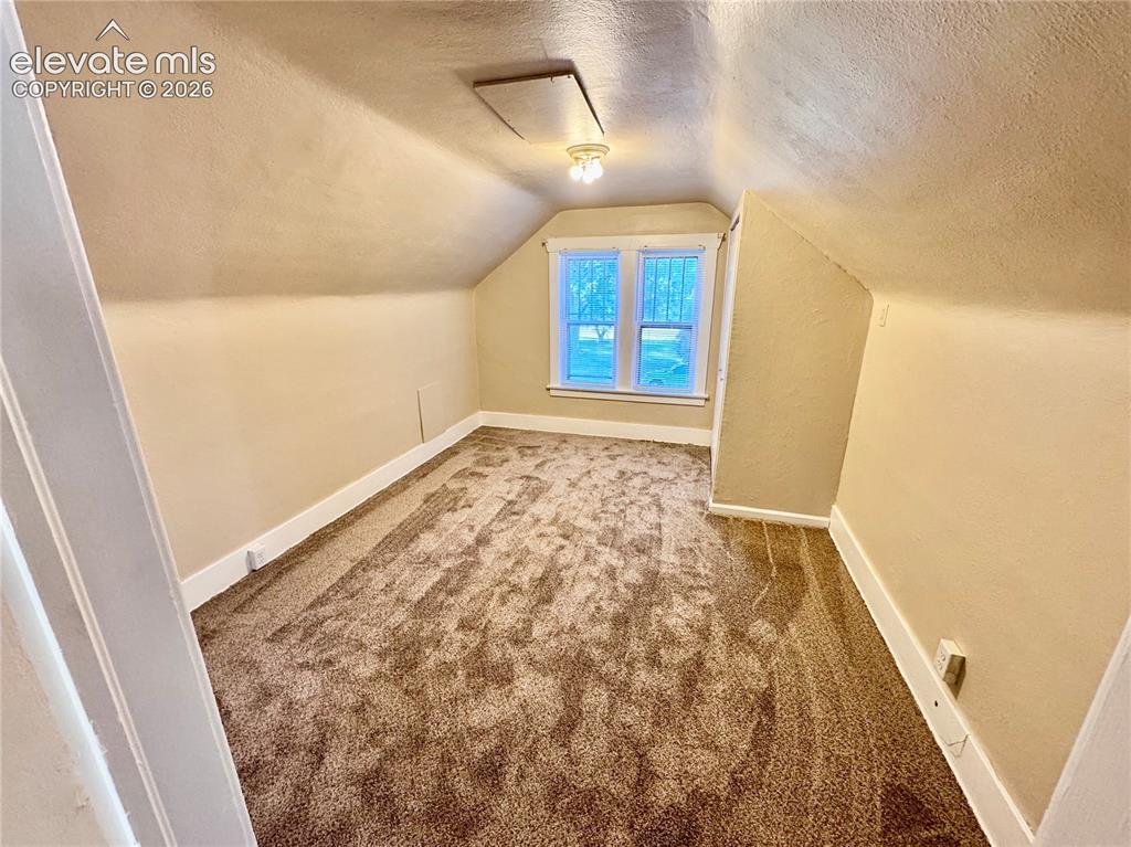Image 33 of 48: Sloped ceilings, window with white trim, recessed access panel, and brown t