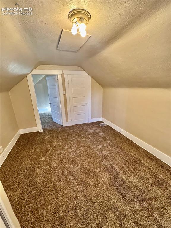 Image 34 of 48: Carpeted flooring, sloped ceiling, flush mount ceiling light, and white tri