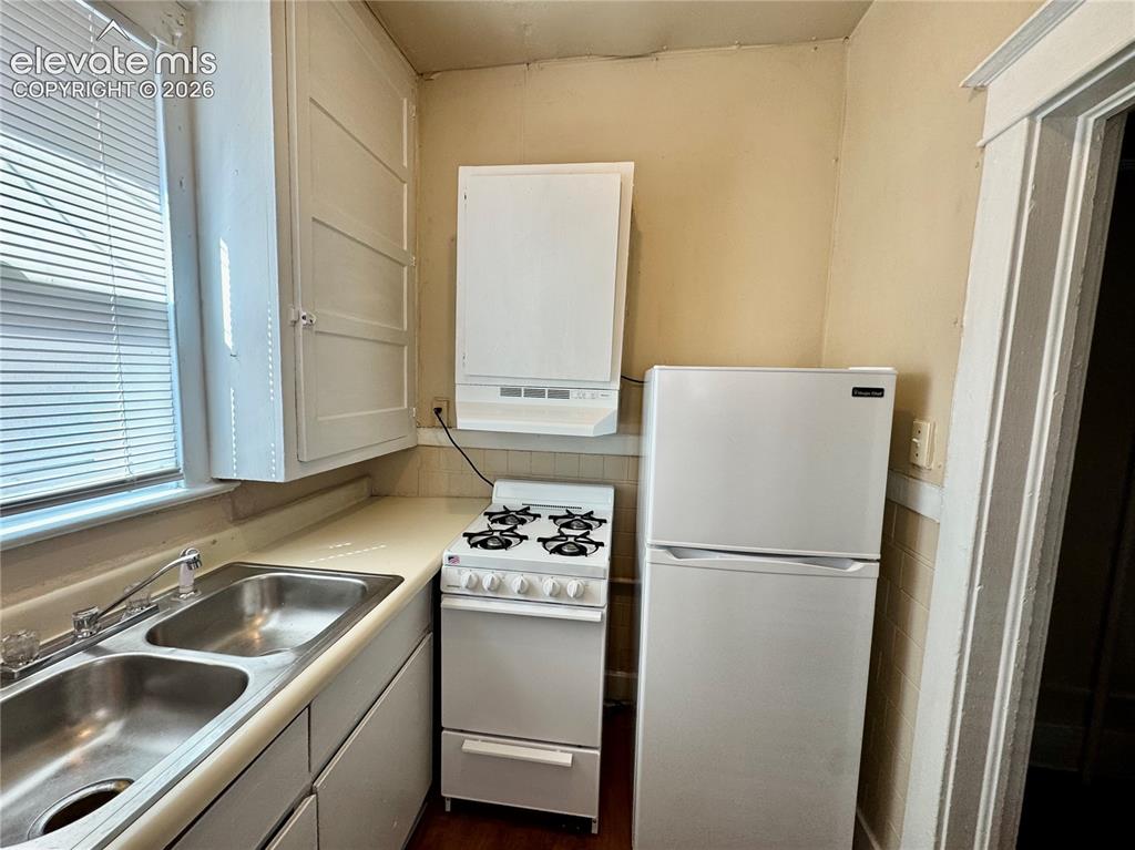 Image 41 of 48: Compact kitchen featuring stainless steel double-basin sink, gas range with