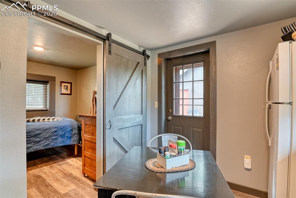 Image 10 of 48: Doorway to outside featuring a barn door, a textured ceiling, wood finished