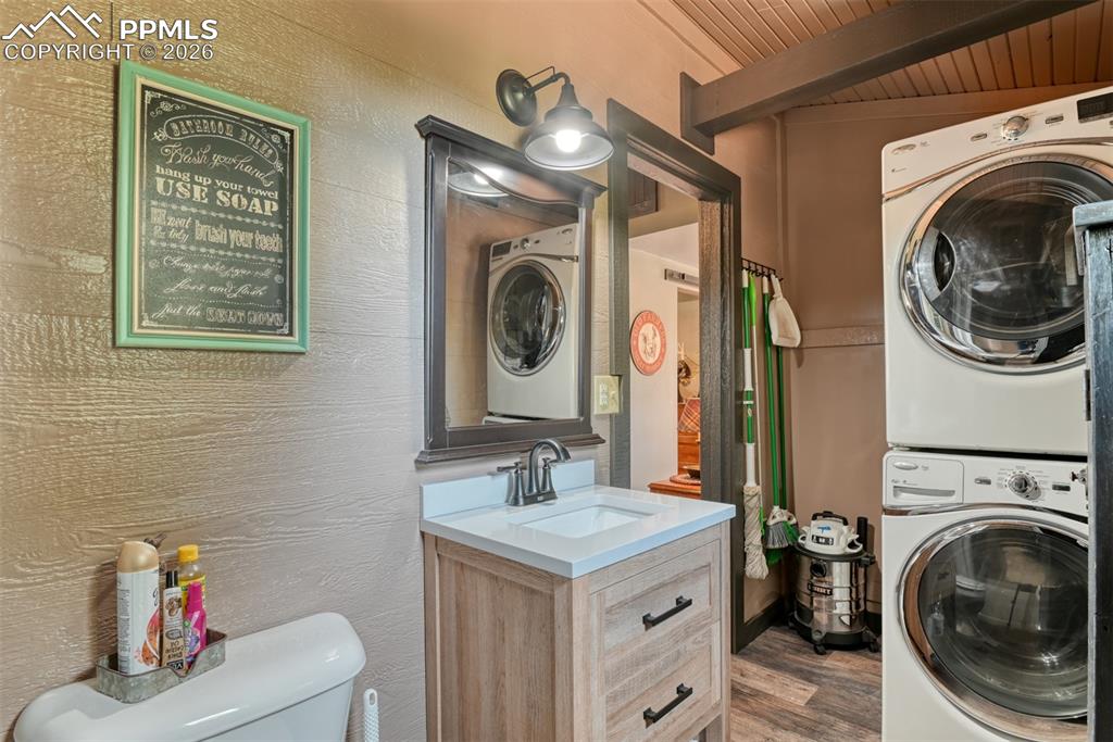 Image 13 of 48: Laundry area featuring stacked washing machine and dryer, wooden ceiling, a