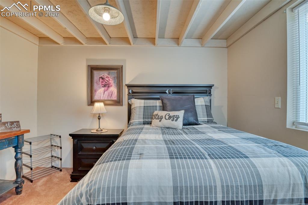 Image 16 of 48: Carpeted bedroom featuring beamed ceiling