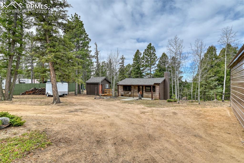 Image 25 of 48: Chalet / cabin featuring a chimney, covered porch, dirt driveway, and view 