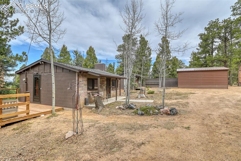 Image 26 of 48: Rear view of house featuring a chimney, a deck, and concrete block siding