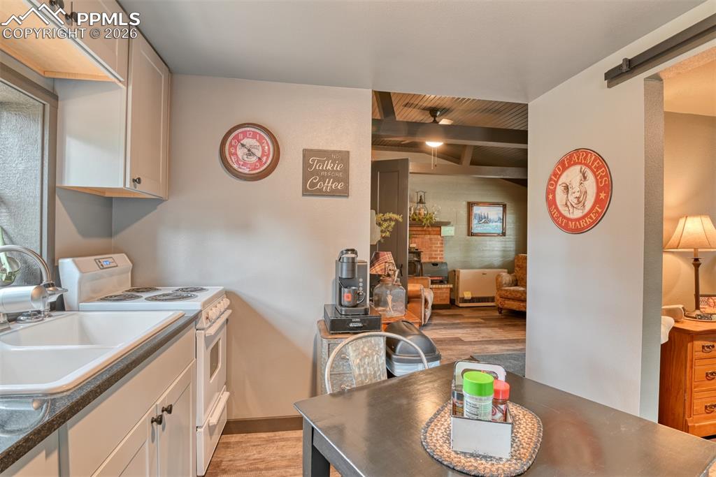 Image 4 of 48: Kitchen featuring electric range, light wood-type flooring, ceiling fan, a 