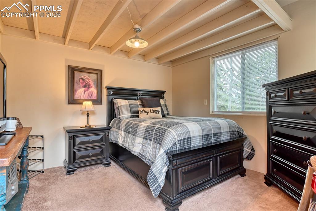 Image 5 of 48: Bedroom featuring light colored carpet and beamed ceiling