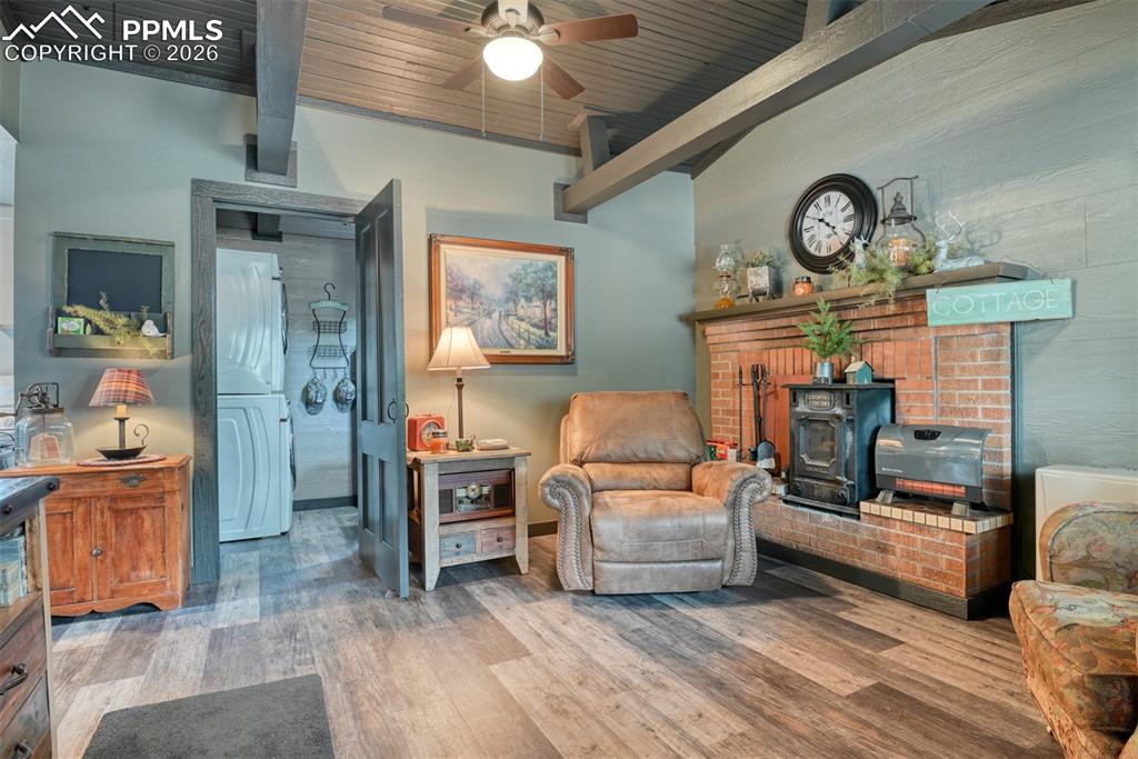 Image 6 of 48: Sitting room with washer / dryer, a wood stove, a wooden ceiling with expos