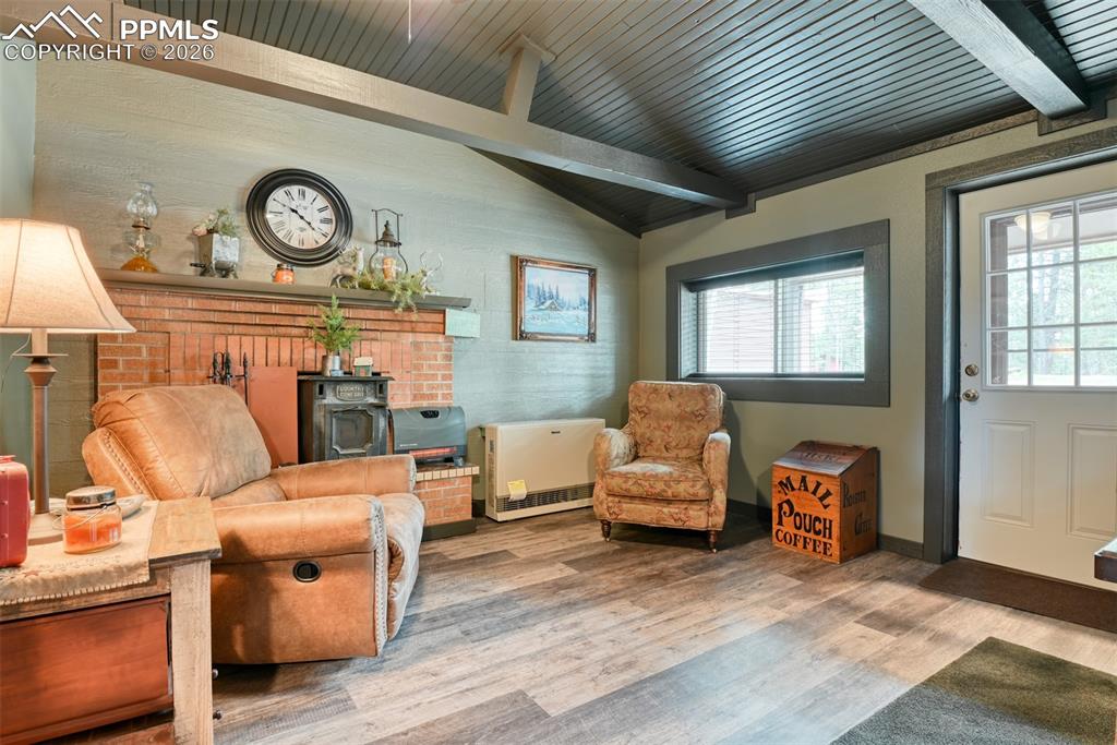 Image 7 of 48: Living area featuring wood finished floors, heating unit, and vaulted ceili