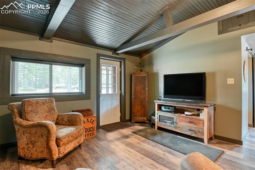 Image 8 of 48: Living area with wood finished floors, lofted ceiling with beams, and woode