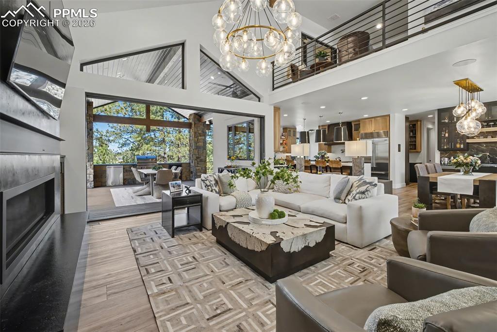Image 10 of 50: Living area featuring hanging lights, a high ceiling, light wood-style floo