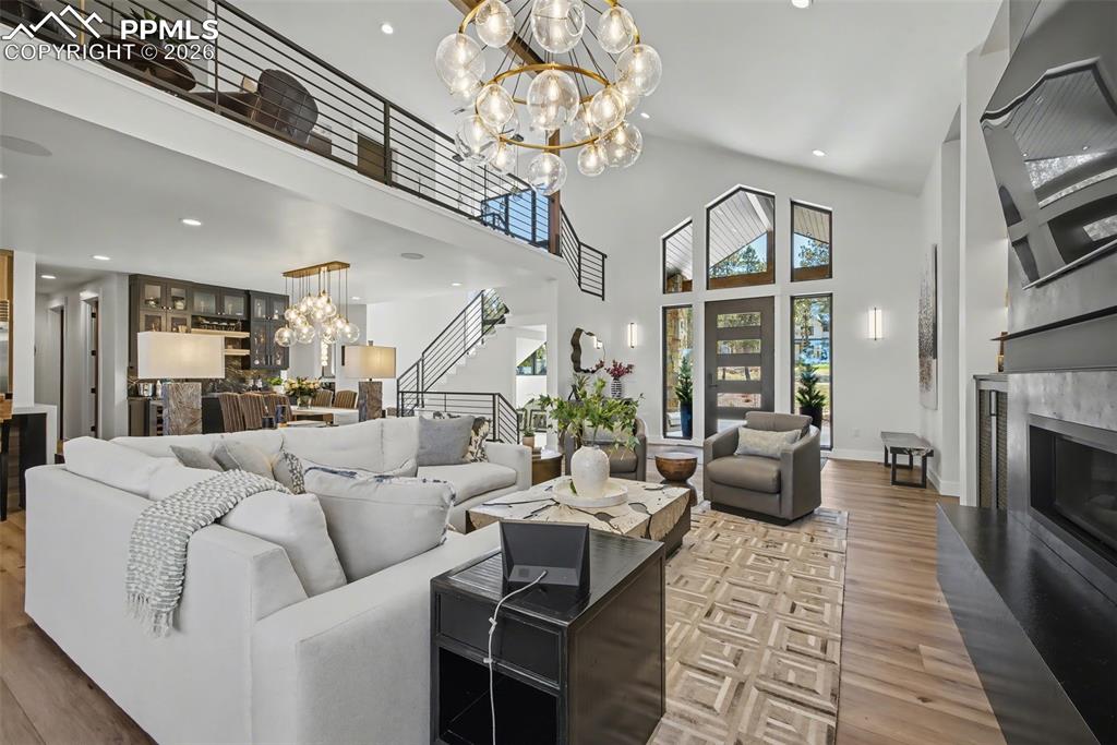 Image 11 of 50: Living area featuring a high ceiling, a fireplace, light wood-style floors,