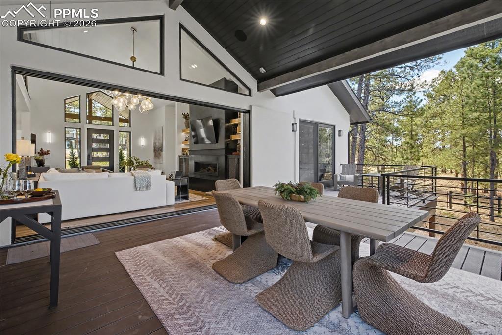 Image 12 of 50: View of patio with a fireplace, outdoor dining area, and a deck
