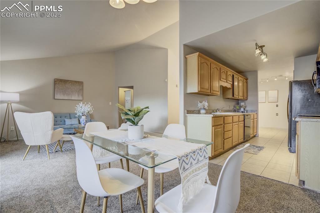 Image 13 of 42: Dining area with light carpet, lofted ceiling, and light tile patterned flo