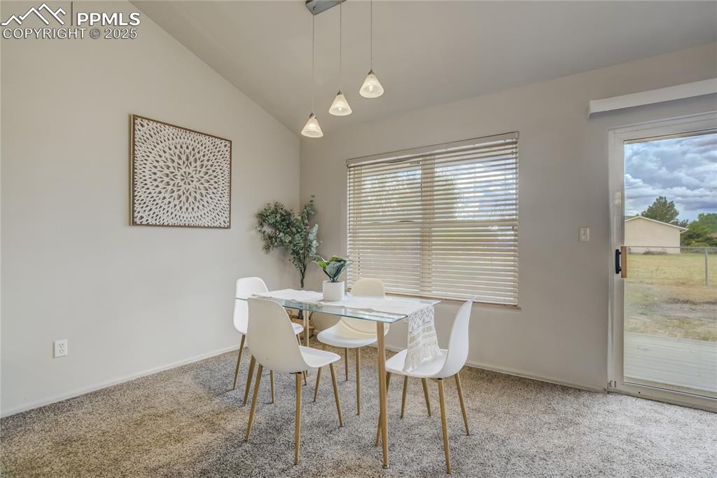Image 14 of 42: Carpeted dining space featuring lofted ceiling and baseboards