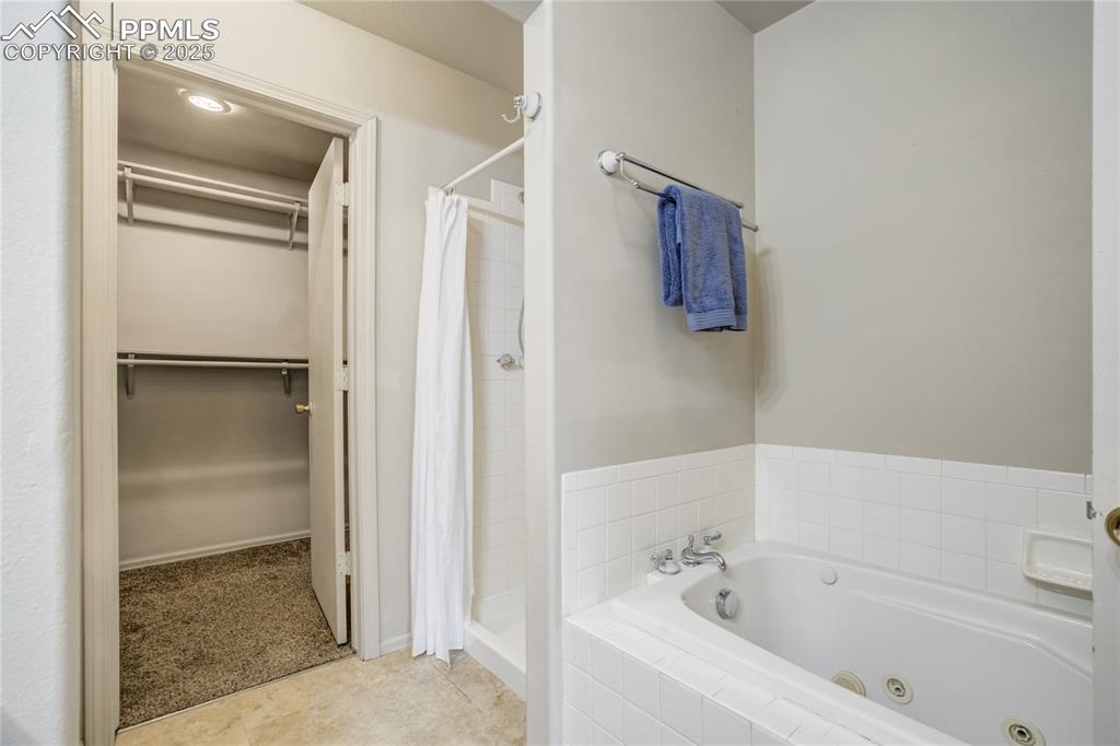 Image 19 of 42: Full bath featuring a shower stall, a spacious closet, a jetted tub, and ti