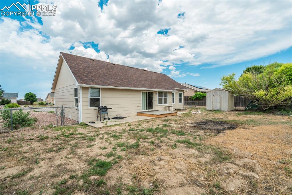 Image 31 of 42: Back of house featuring a shed, a fenced backyard, a patio, and roof with s