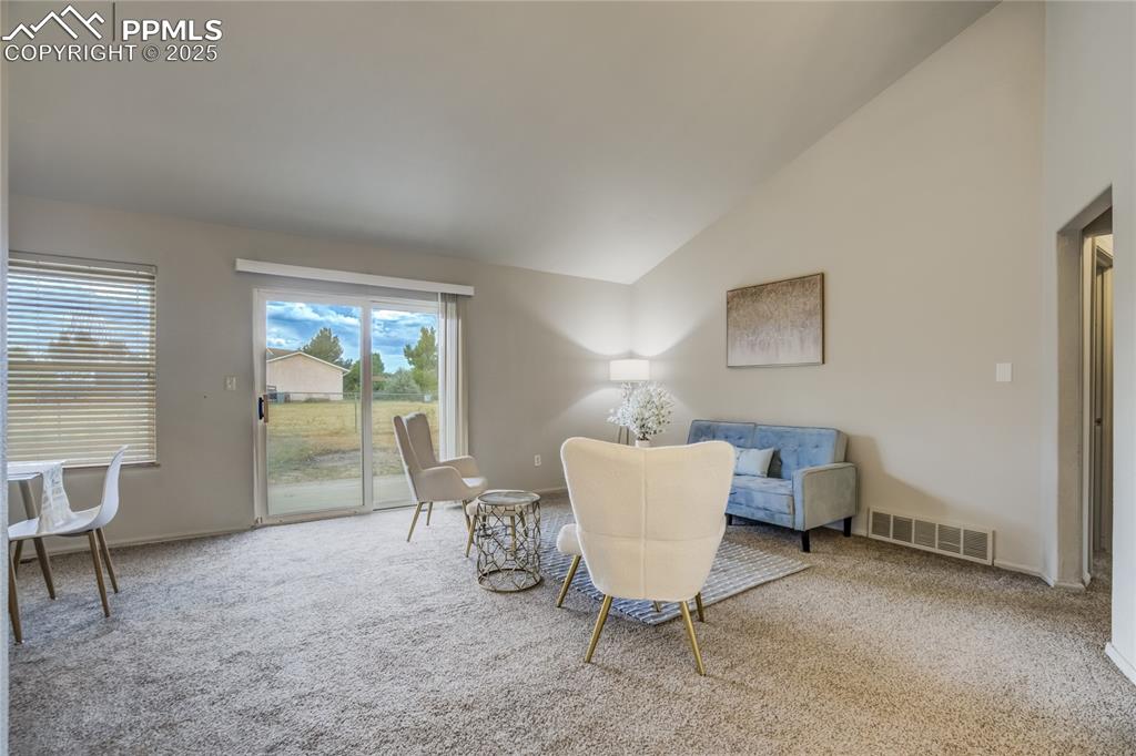 Image 4 of 42: Living room with walk-out access to backyard, vaulted ceiling and carpet fl