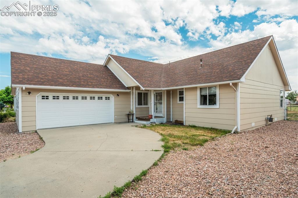 Image 41 of 42: Ranch-style house featuring a shingled roof, a garage, and concrete drivewa