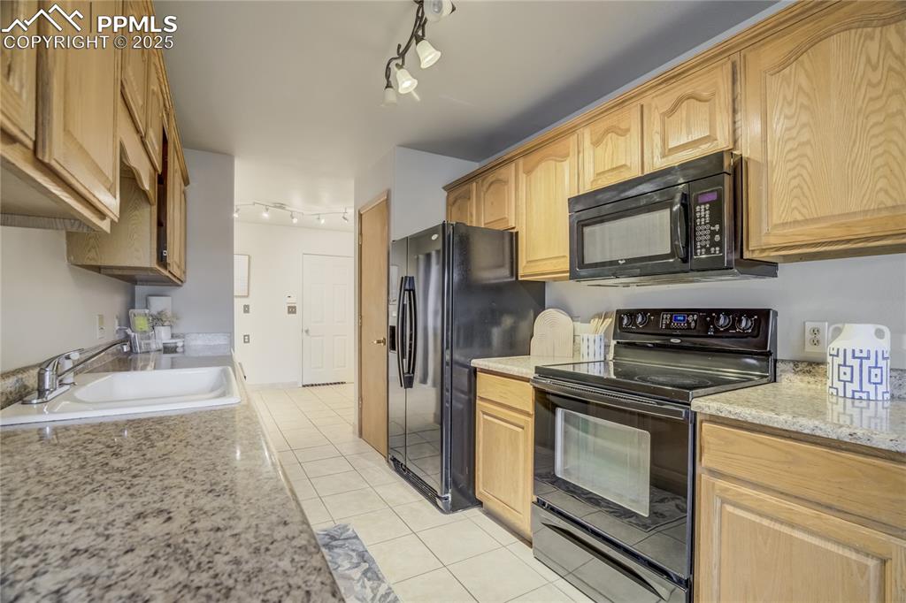 Image 9 of 42: Kitchen featuring black appliances, light tile patterned flooring, track li