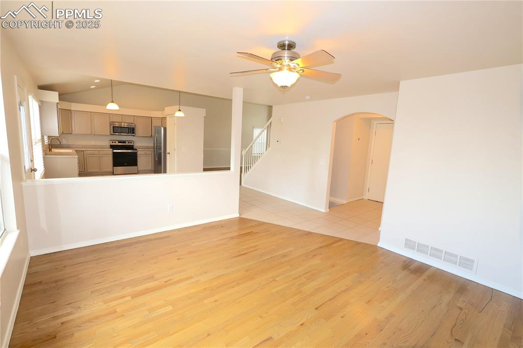 Image 10 of 39: Unfurnished living room with arched walkways, light wood-type flooring, a c