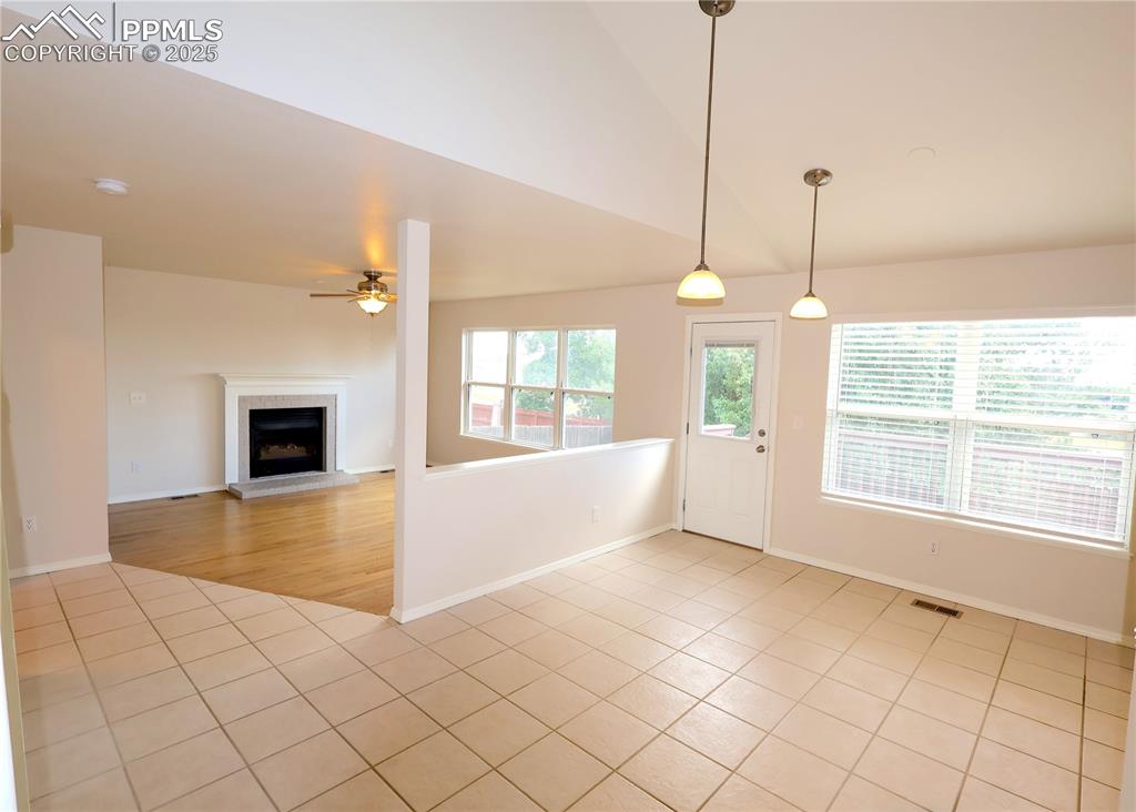 Image 11 of 39: Foyer with light tile patterned floors, ceiling fan, a fireplace with raise