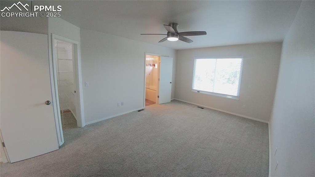 Image 12 of 39: Unfurnished bedroom with light colored carpet, connected bathroom, and a ce