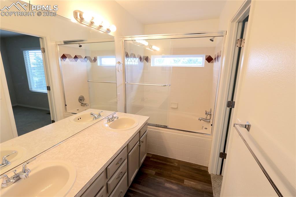 Image 15 of 39: Bathroom with combined bath / shower with glass door, wood finished floors,