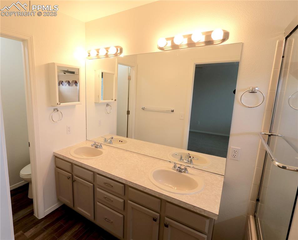 Image 16 of 39: Bathroom featuring double vanity, wood finished floors, and an enclosed sho