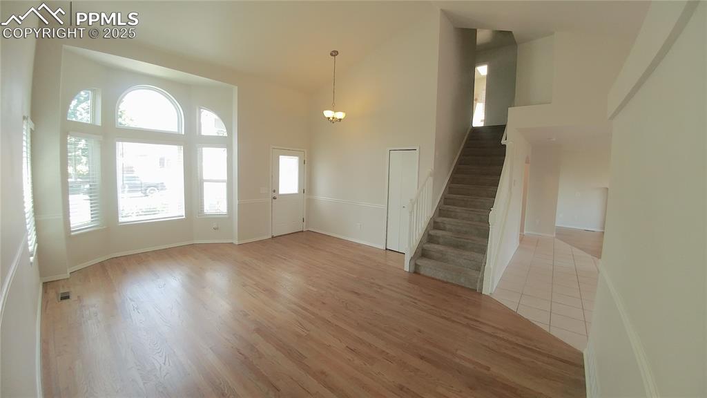 Image 3 of 39: Foyer featuring a chandelier, stairs, high vaulted ceiling, and light wood-