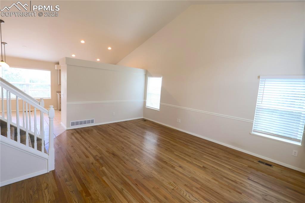 Image 4 of 39: Empty room featuring lofted ceiling, wood finished floors, and recessed lig