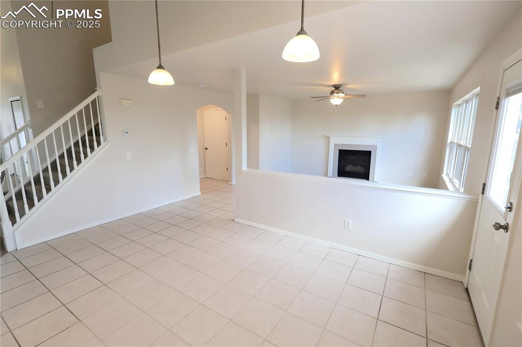 Image 8 of 39: Unfurnished living room featuring a ceiling fan, stairs, arched walkways, a