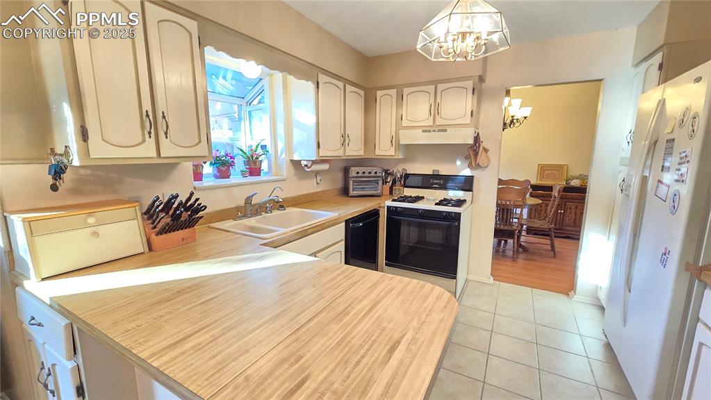 Image 17 of 42: Kitchen featuring light countertops, white fridge with ice dispenser, gas r