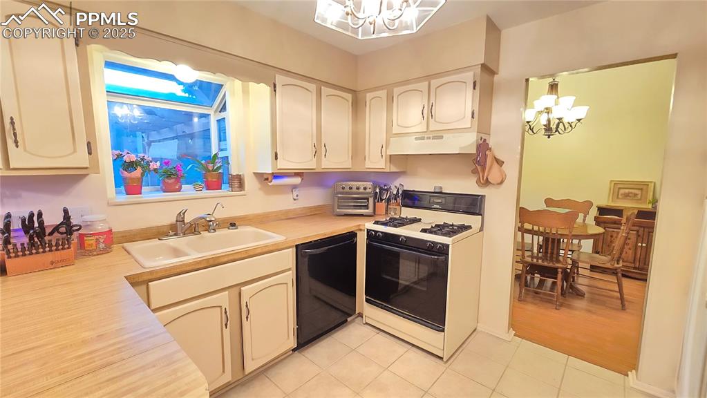 Image 18 of 42: Kitchen featuring a chandelier, white range with gas stovetop, and light co