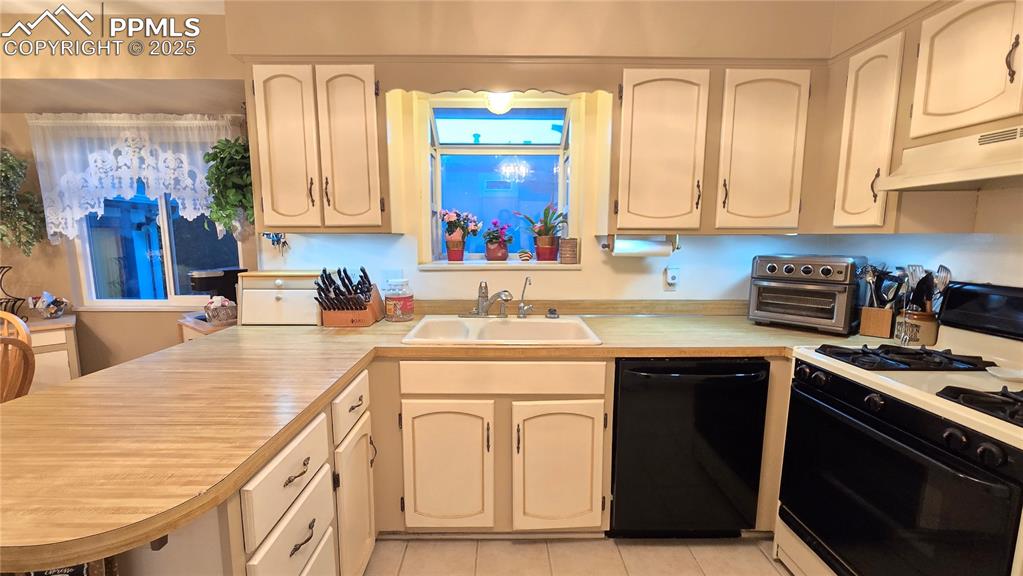 Image 19 of 42: Kitchen featuring a peninsula, black appliances, light countertops, light t