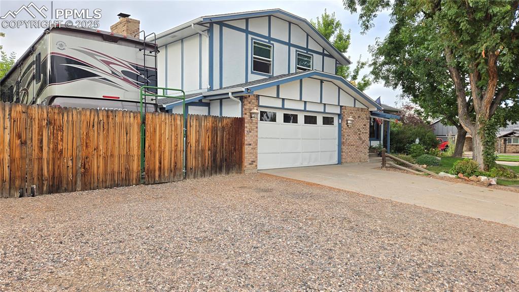 Image 2 of 42: View of front facade with brick siding, driveway, board and batten siding, 