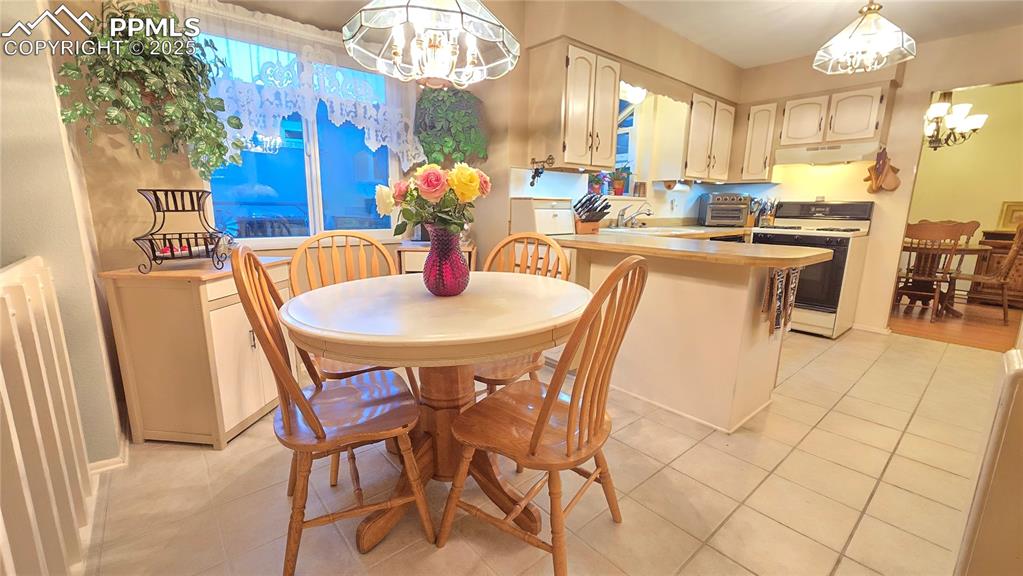 Image 20 of 42: Dining area with a chandelier and light tile patterned floors