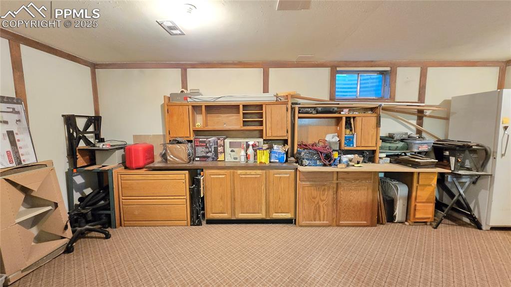 Image 24 of 42: Below grade area with freestanding refrigerator and light colored carpet