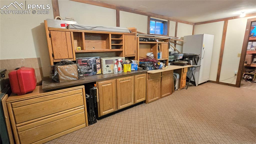 Image 25 of 42: Kitchen with dark countertops, brown cabinets, freestanding refrigerator, l