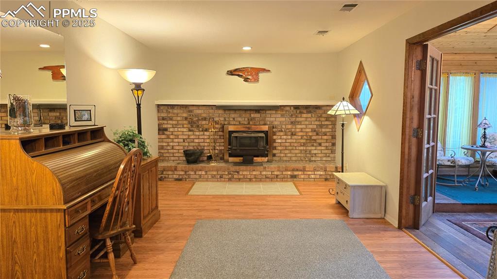 Image 28 of 42: Living area featuring light wood-type flooring, a wood stove, and recessed 