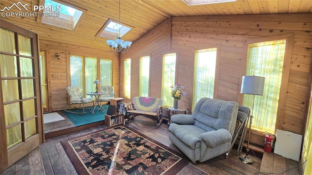 Image 29 of 42: Living area with wood walls, dark wood-style flooring, wood ceiling, a skyl