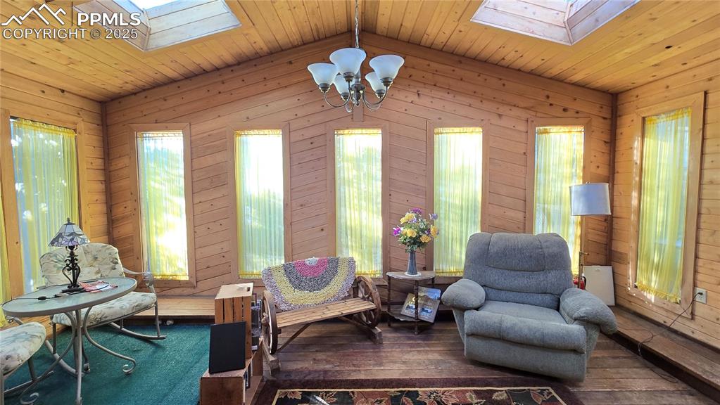 Image 30 of 42: Living area featuring a skylight, wood walls, wood ceiling, lofted ceiling,