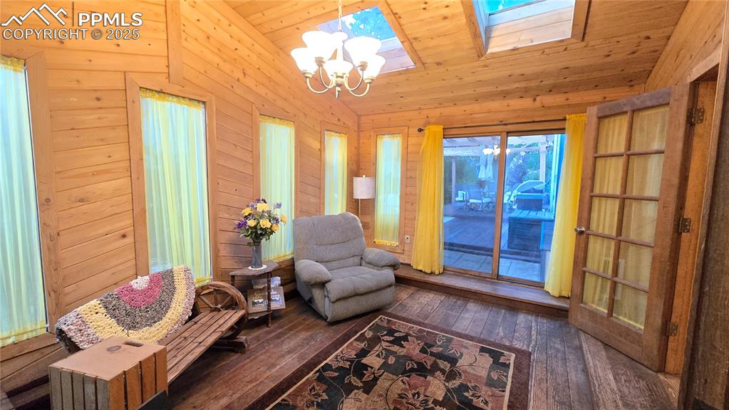 Image 31 of 42: Living area with lofted ceiling, dark wood finished floors, wooden walls, a