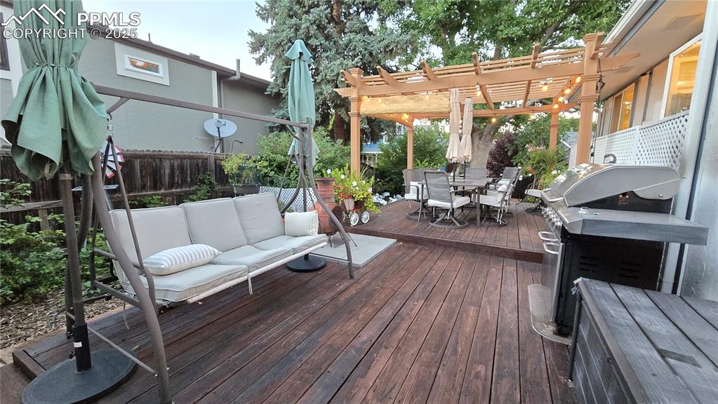 Image 32 of 42: Wooden terrace with outdoor dining area, a grill, and a pergola