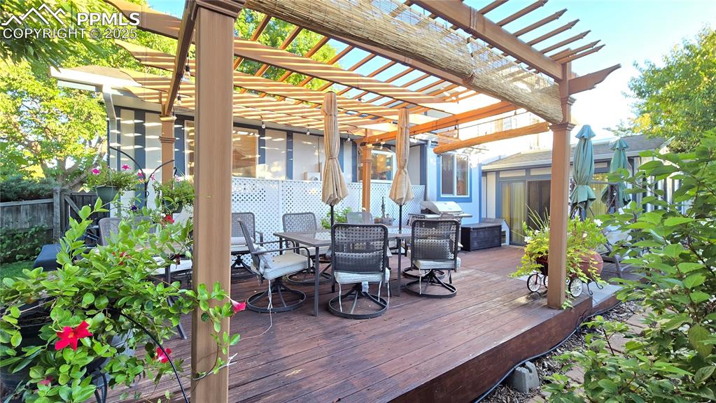 Image 35 of 42: Wooden terrace with outdoor dining space and an outbuilding