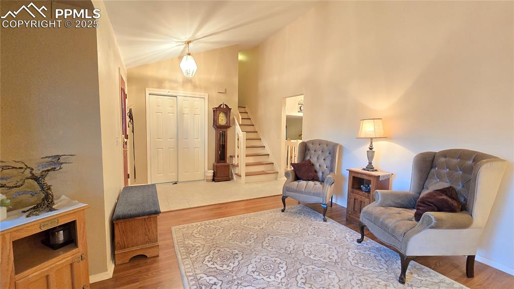 Image 9 of 42: Living area featuring wood finished floors, lofted ceiling, and stairway